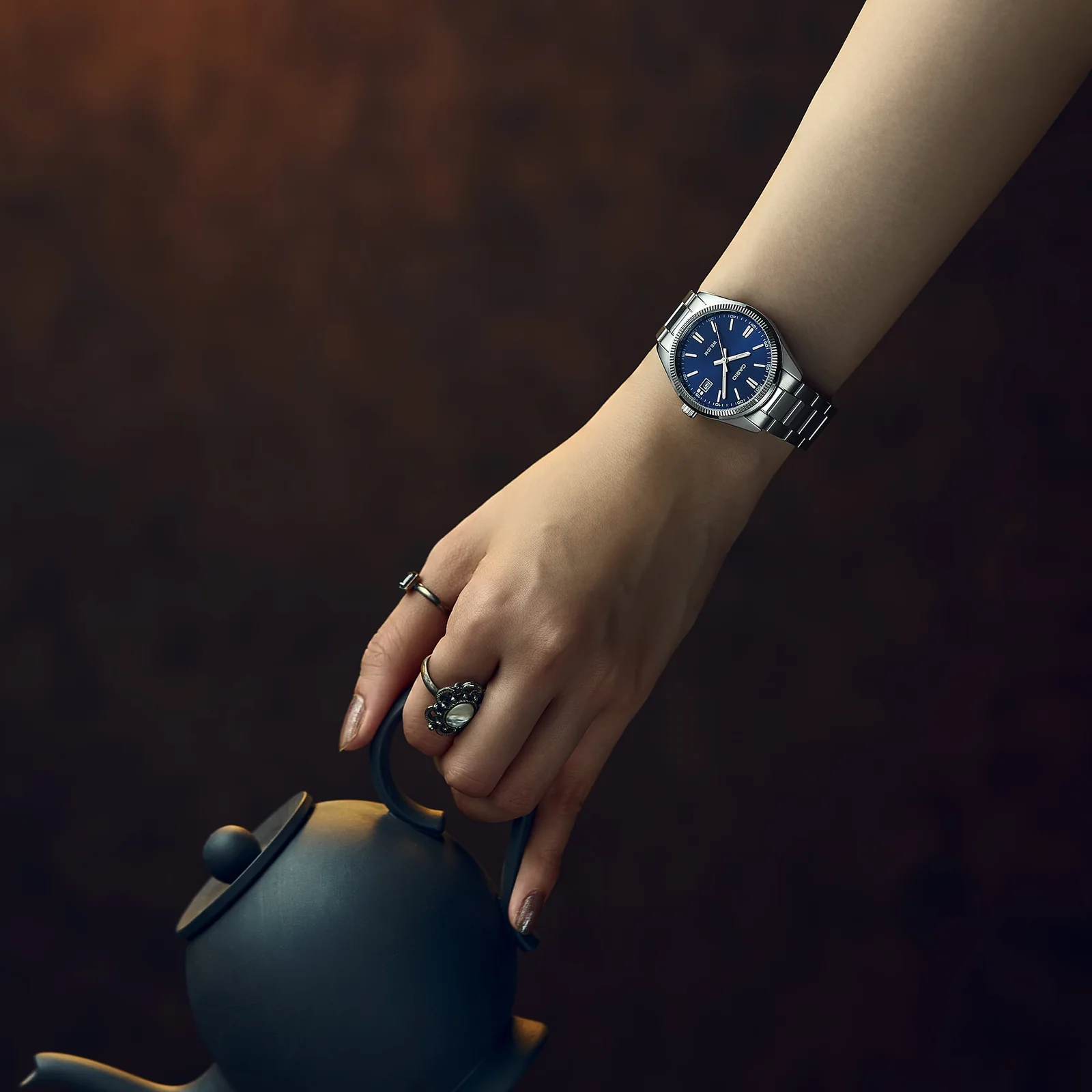 Eine Frau hält eine japanische Teekanne in der Hand und trägt die silberne Armbanduhr UTP-1302PD-2A1VEF am Handgelenk