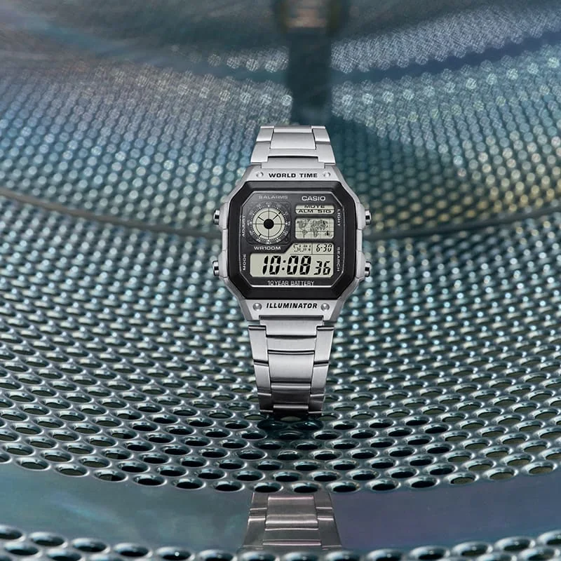 Die CASIO Uhr AE-1200WHD-1AV wird in einem Waschsalon auf eine Metalloberfläche gelegt.