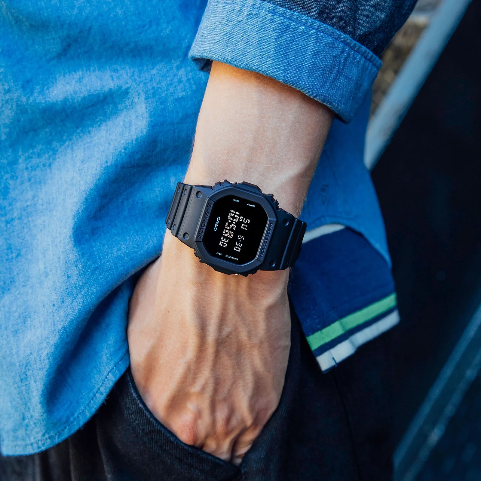 Die Digitaluhr DW-5600UBB-1 Digitaluhr am Handgelenk eines Mannes, der seine Hand in die Hosentasche steckt.