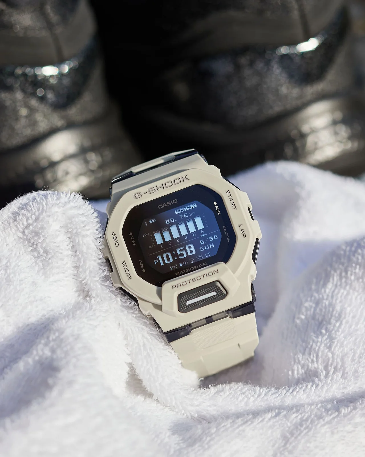 Die G-SHOCK Armbanduhr GBD-200UU-9 von vorn, drapiert in einem Frottee-Handtuch neben Sportschuhen.