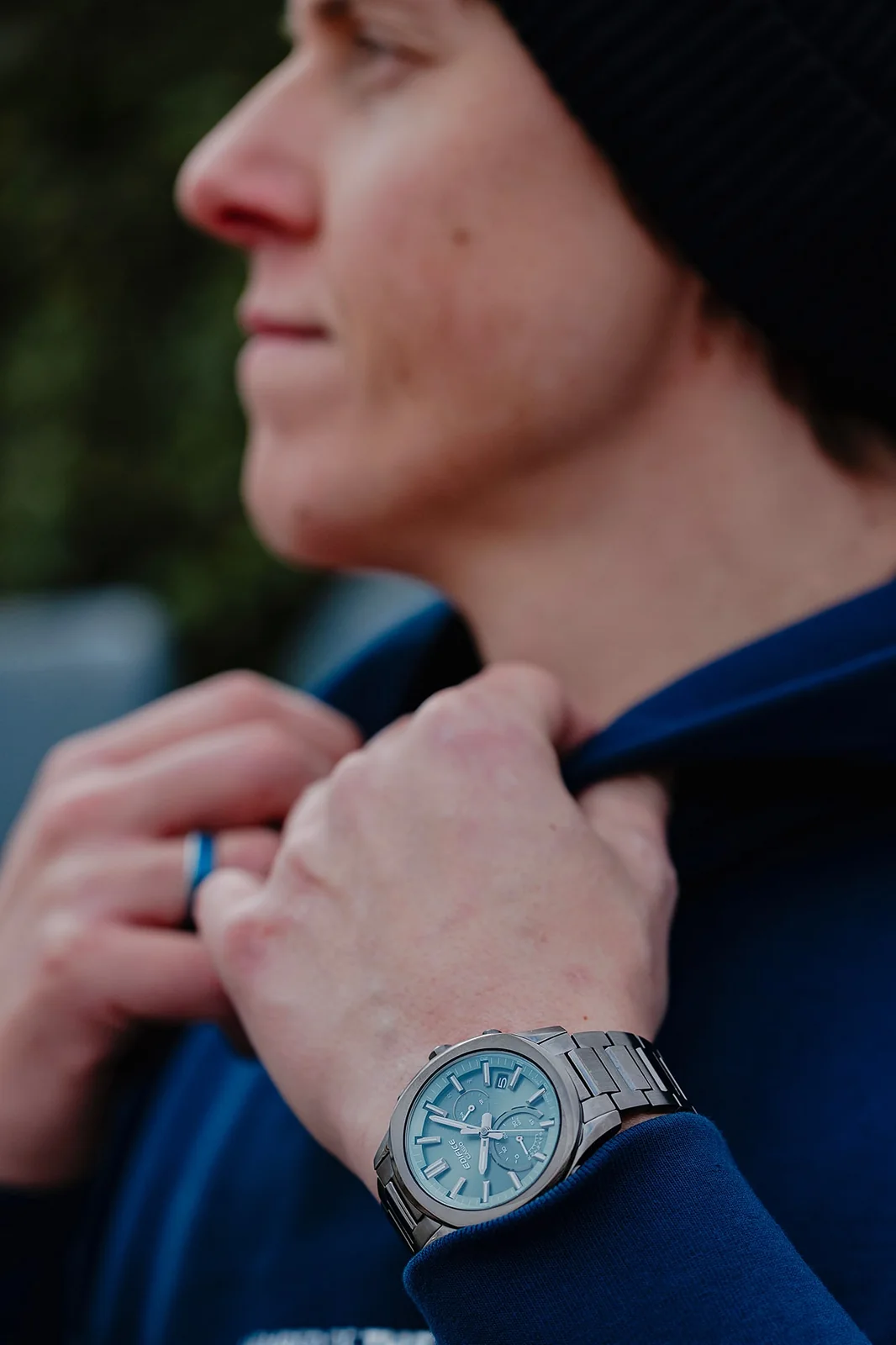 Ein Mann mit einem blauen Oberteil und einer Mütze trägt die EDIFICE Armbanduhr EQB-1300DC-3AEF am Handgelenk