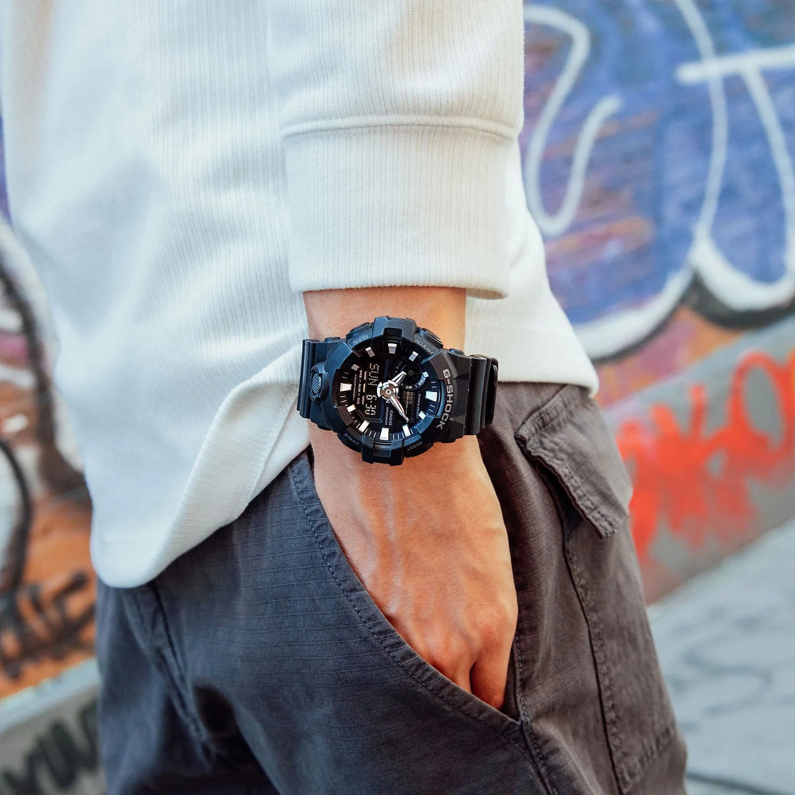 Die G-SHOCK Armbanduhr GA-700-1B am Handgelenk einer Person in Außenumgebung.