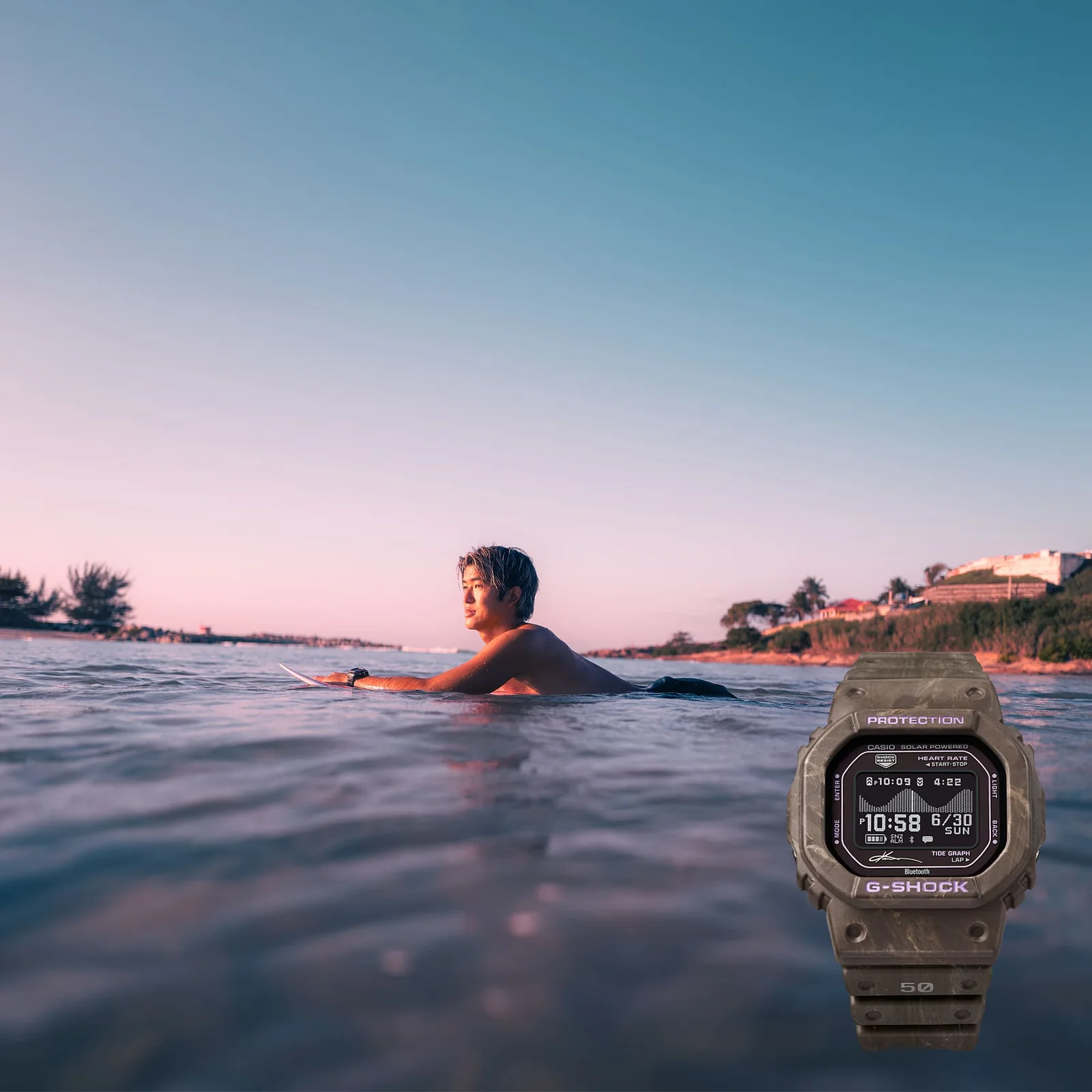 Der Surfer Kanoa Igarashi liegt im Wasser auf seinem Surfbrett und unten rechts in der Bildecke ist die Armbanduhr GBX-H5600KI-5ER abgebildet