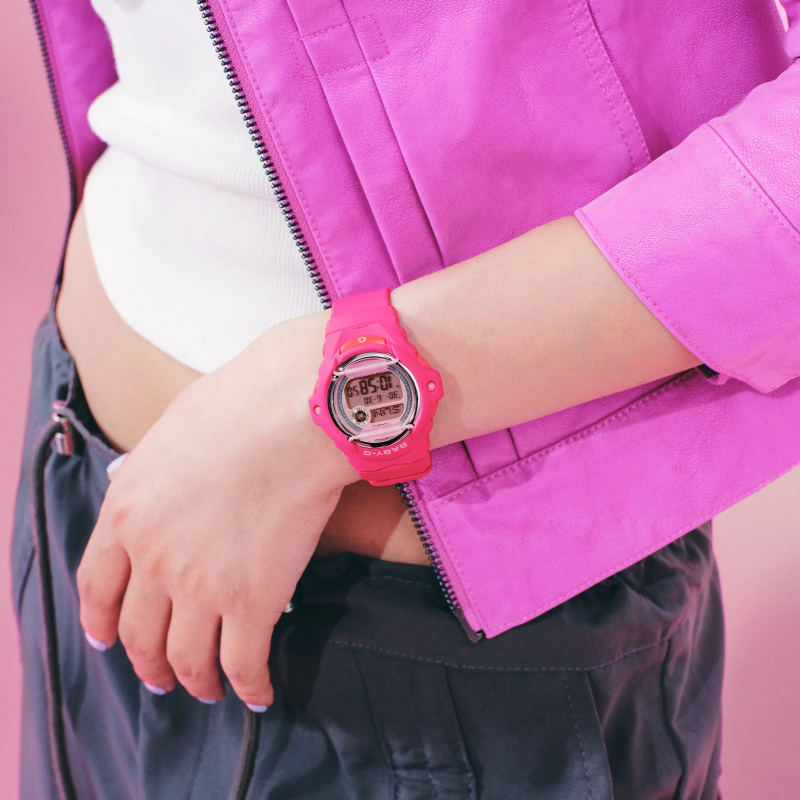 Eine Frau mit einer pinken Lederjacke trägt die Armbanduhr BG-169KB-4B1ER von BABY-G am Handgelenk