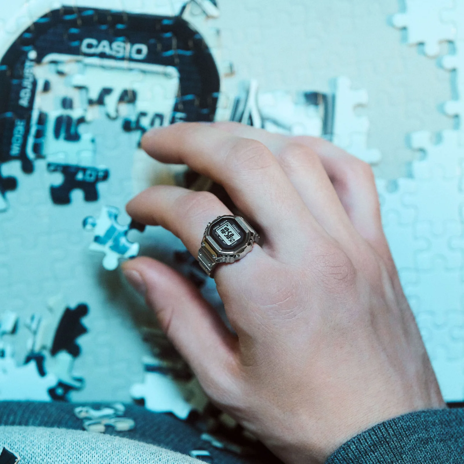 Close-Up auf eine Hand, die am Zeigefinger die CASIO Ring Watch mit Digitalanzeige trägt und ein Puzzle zusammenlegt.