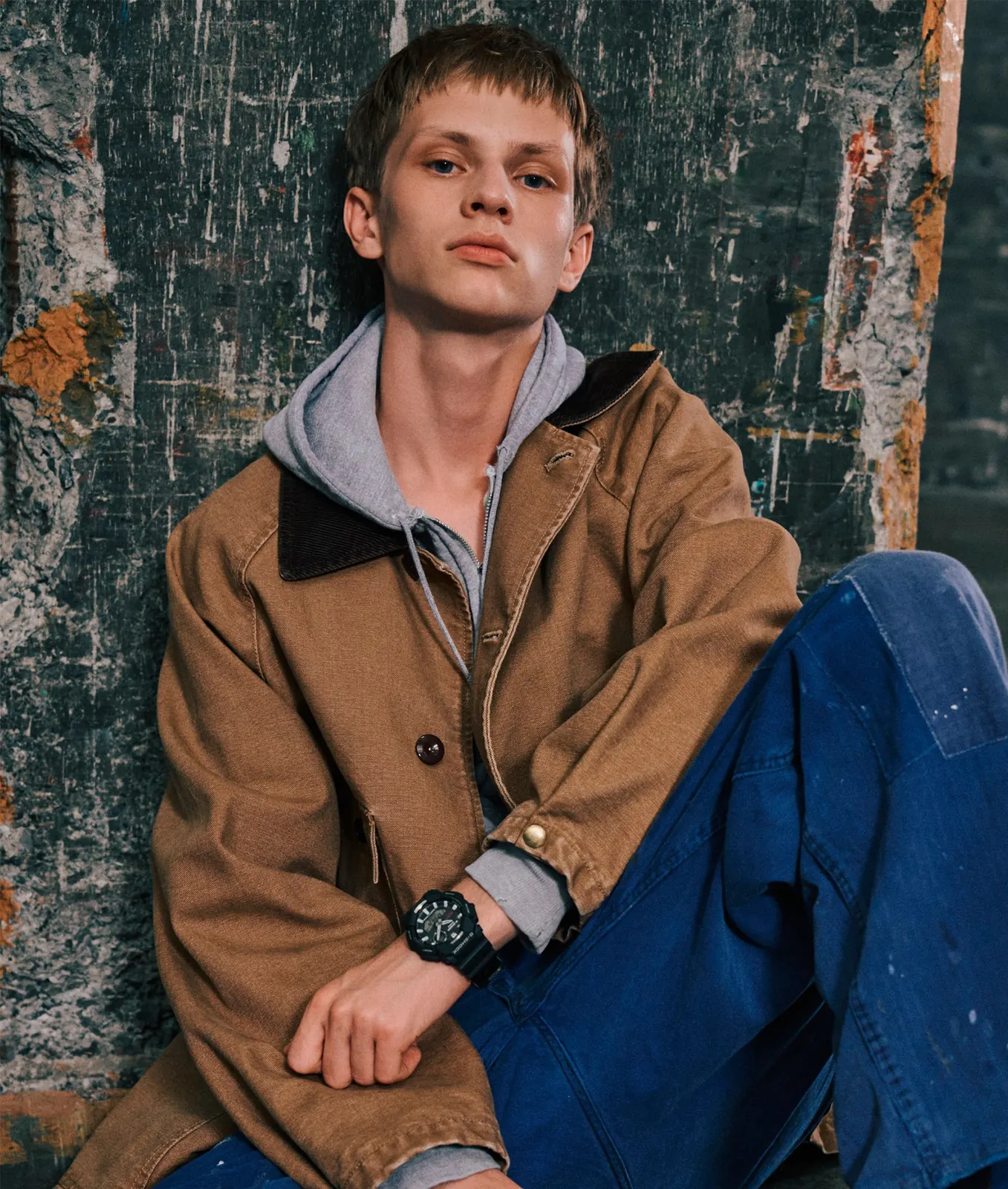 Ein Mann mit einer hellbraunen Jacke und einer blauen Jeanshose trägt die GA-B010-1AER am Handgelenk