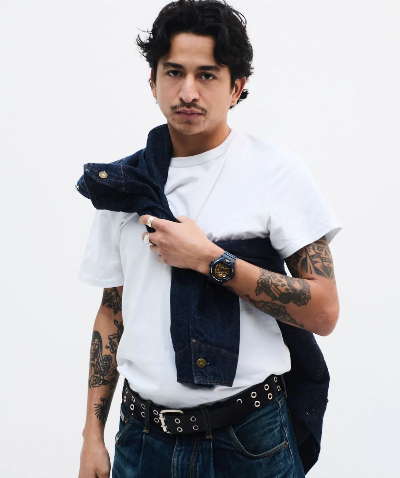 Ein Mann mit einem weißen T-Shirt und einer schwarzen Jacke trägt die DW-6900CF-1ER am Handgelenk
