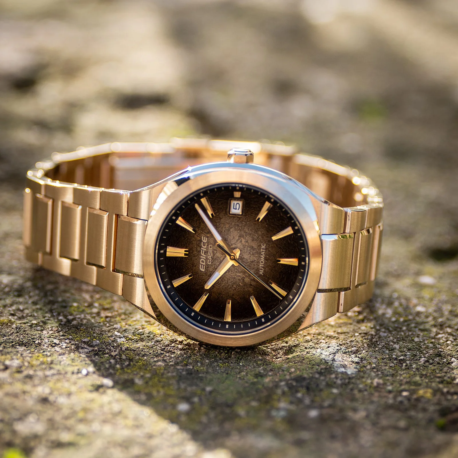 Die goldene Armbanduhr EFK-200DG-5AER liegt auf einer steinernen Oberfläche