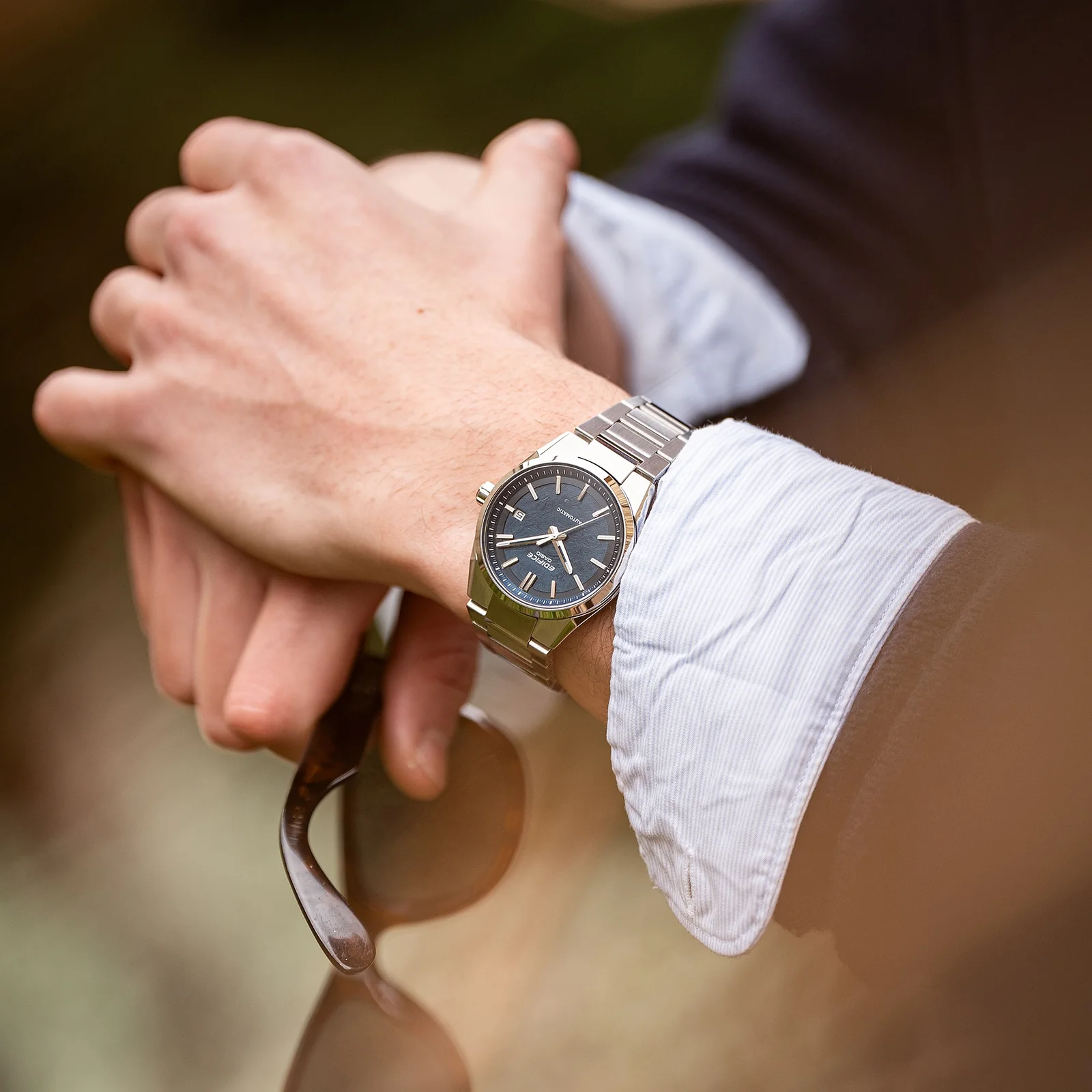 Ein Mann trägt die EFK-110D-2A am Handgelenk und hält eine Sonnenbrille in der Hand