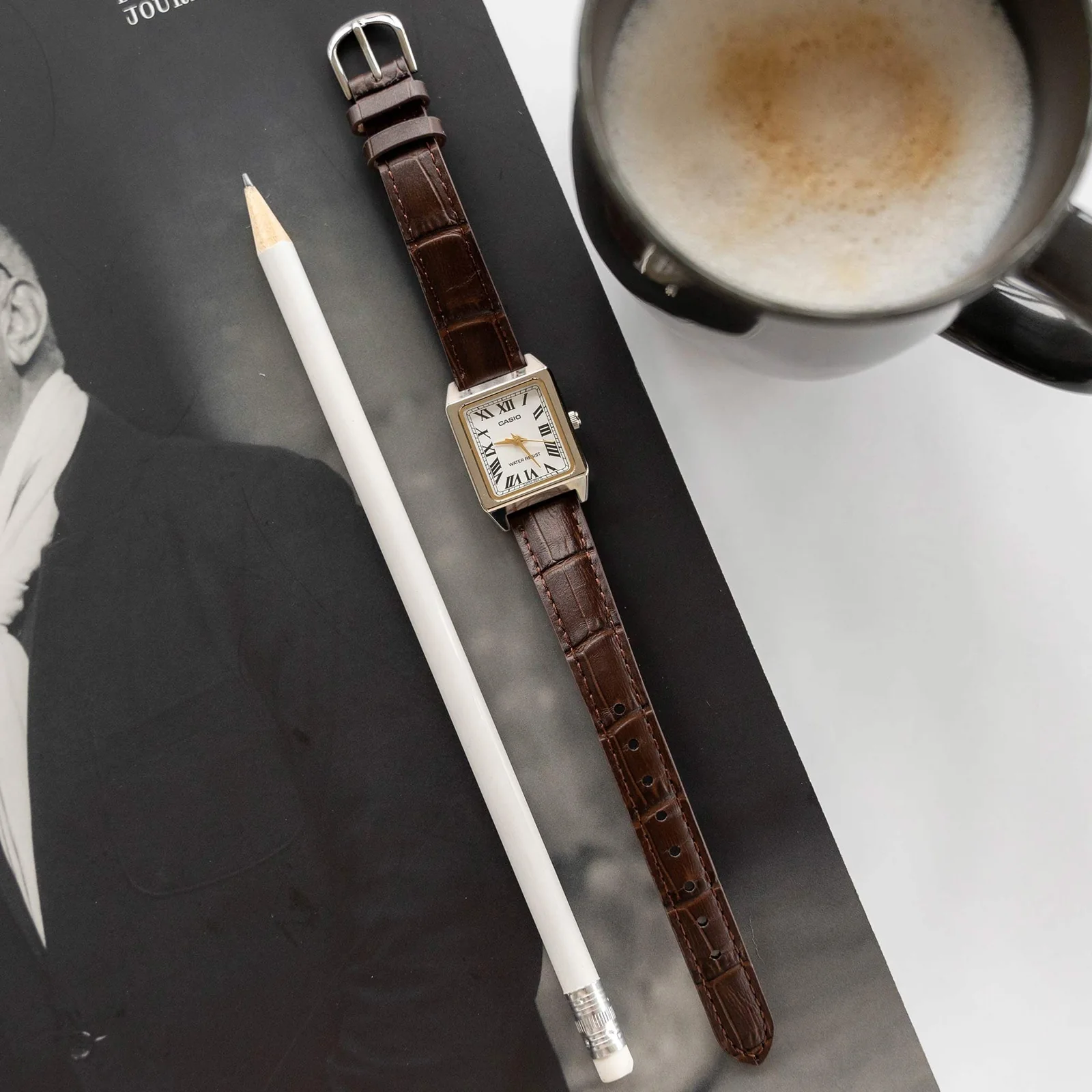 Komplettansicht der flach liegenden CASIO TIMELESS COLLECTION Armbanduhr LTP-B150L-7B2 auf einem Tisch neben einem Bleistift.