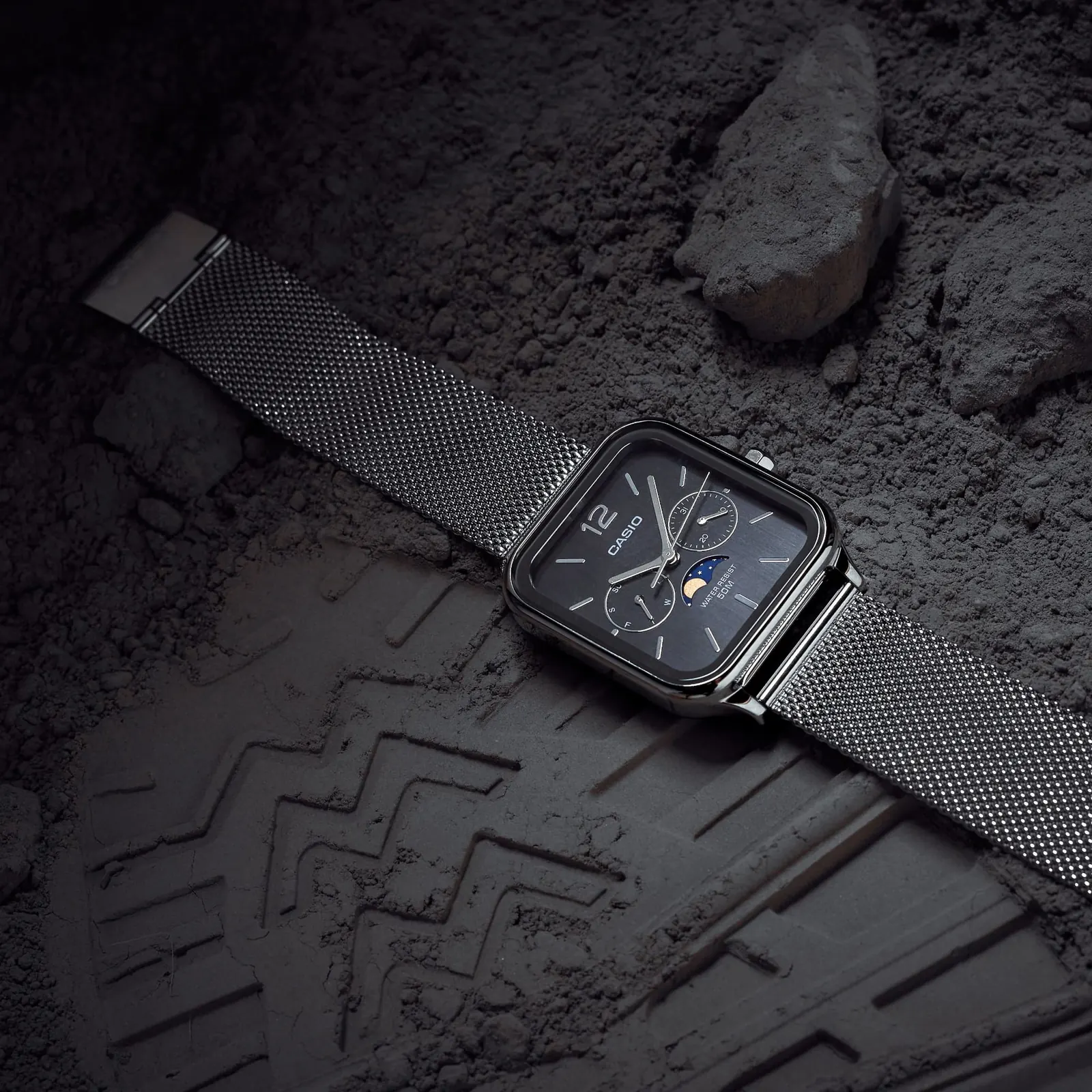 Die CASIO TIMELESS COLLECTION Armbanduhr MTP-M305M-1AV dekorativ drapiert neben einem Schuhabdruck in staubigem Boden.