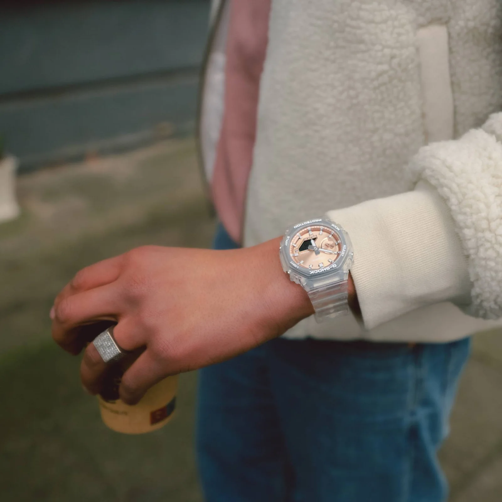Ein Mann trägt die GA-2100BM-7A5 am Handgelenk und hat ein pastellfarbenes T-Shirt und weiße Jacke an.