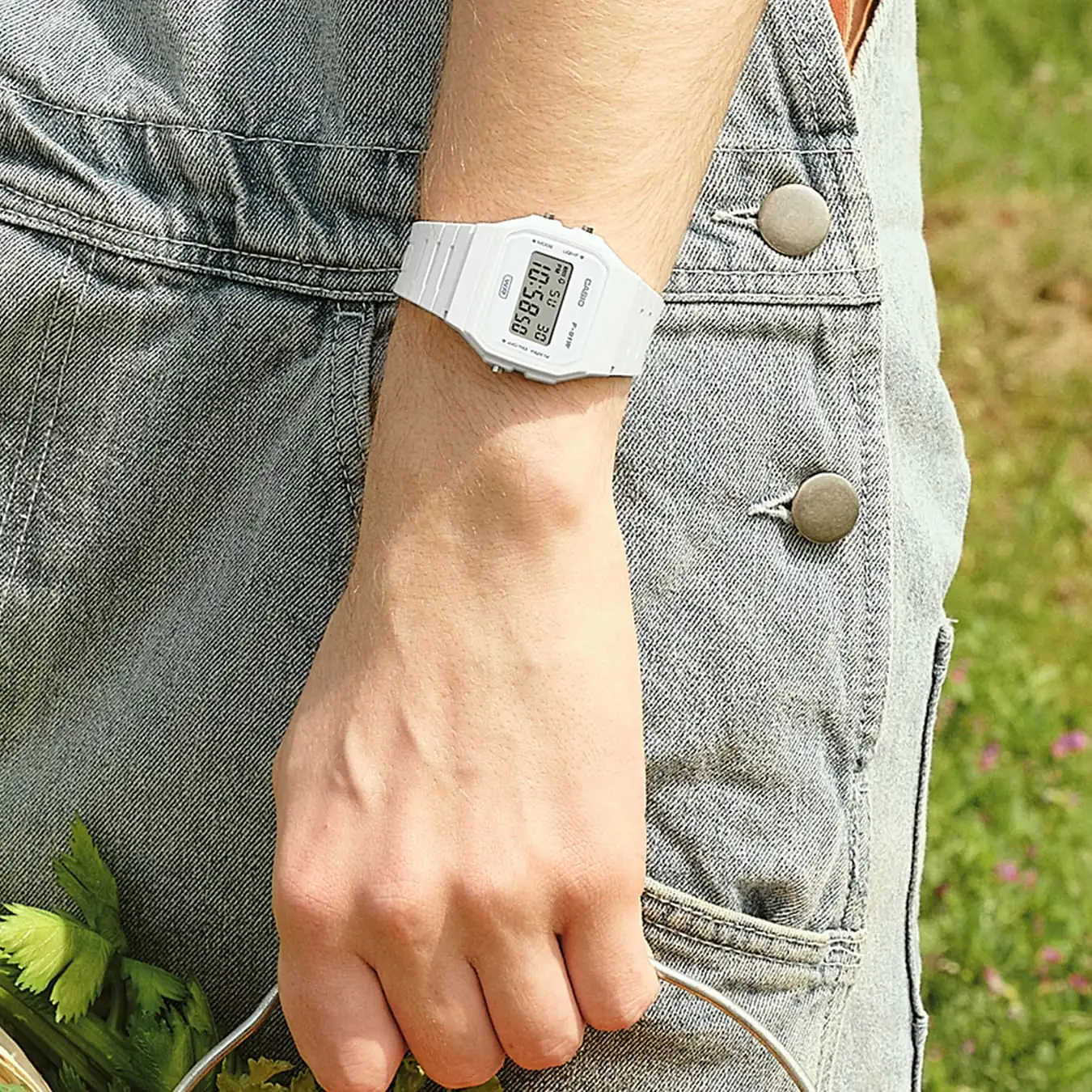 Die CASIO TIMELESS COLLECTION Armbanduhr F-91WB-7A am Handgelenk einer Person in Außenumgebung.