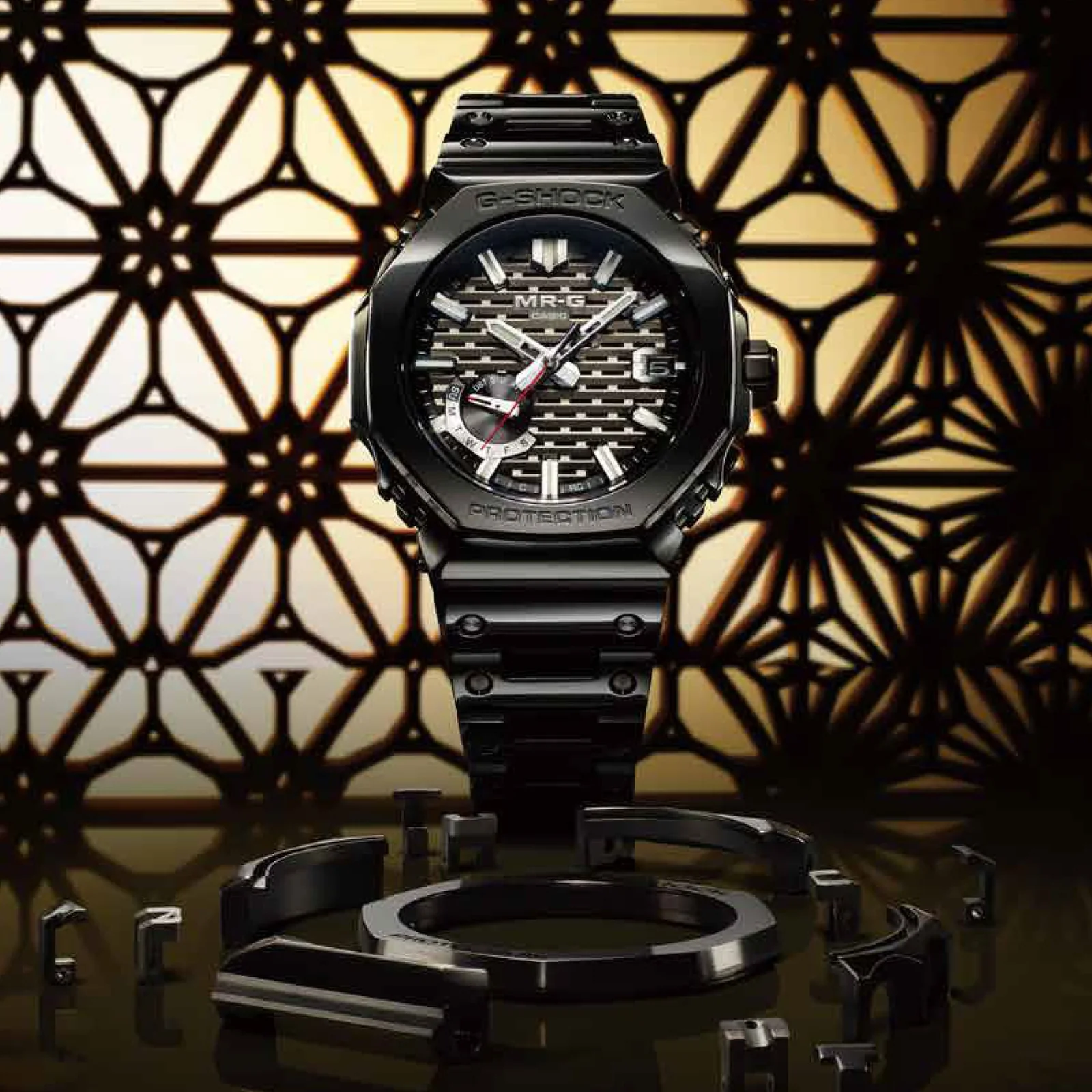 Gehäuse und Armband der G-SHOCK Armbanduhr MRG-B2100B-1A direkt von vorn vor einem traditionellen japanischen Muster in Schwarz-Weiß.