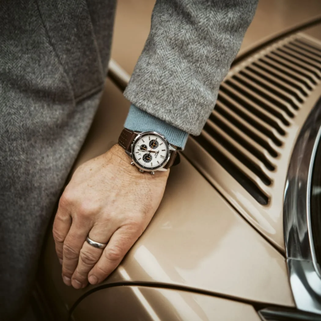 Nahaufnahme der EDIFICE EFR-575L-7A Uhr am Handgelenk eines Mannes, der sich auf eine beigefarbene Motorhaube stützt