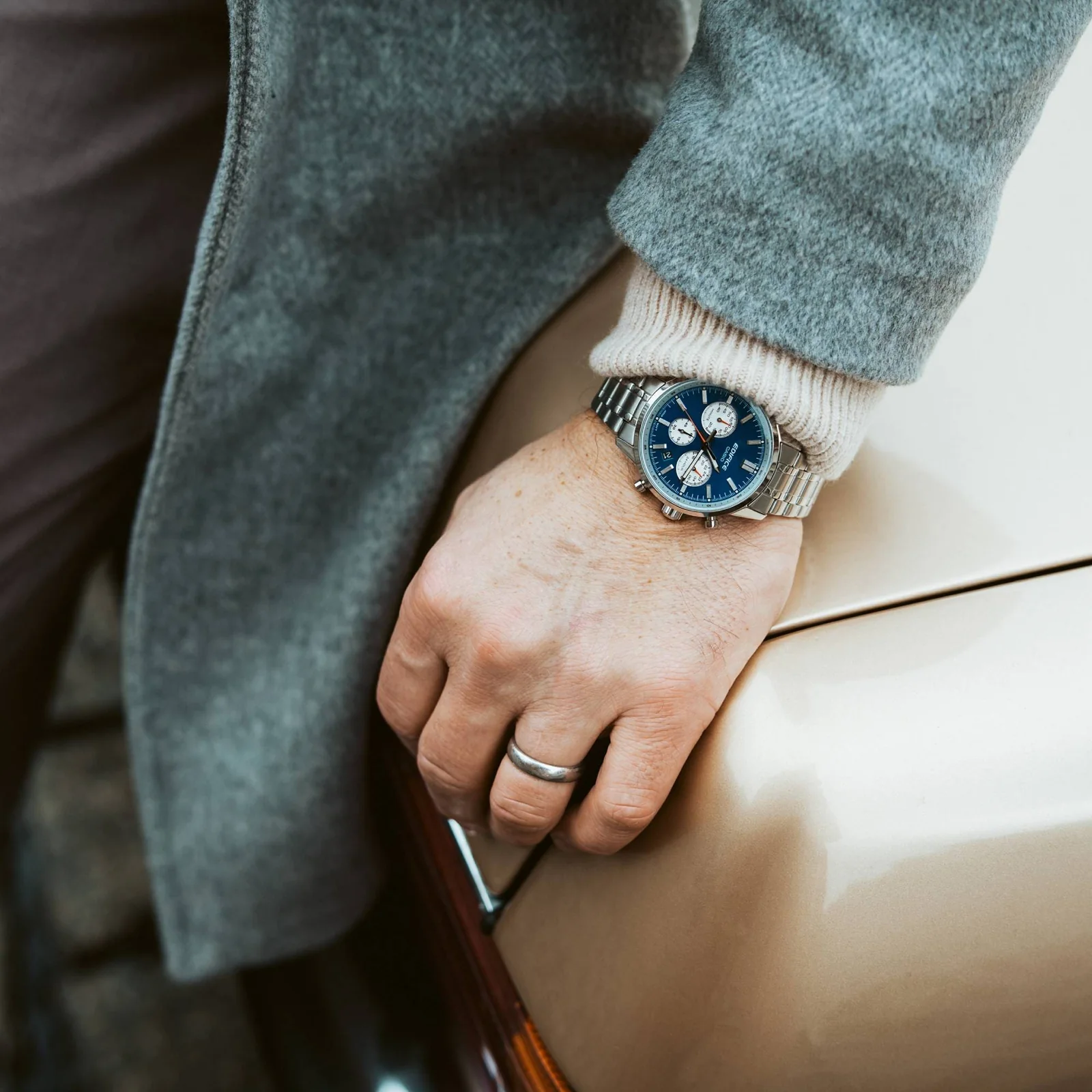 Nahaufnahme der blauen EDIFICE-Uhr EFR-575D-2AEF am Handgelenk eines Mannes in einem grauen Wollmantel.