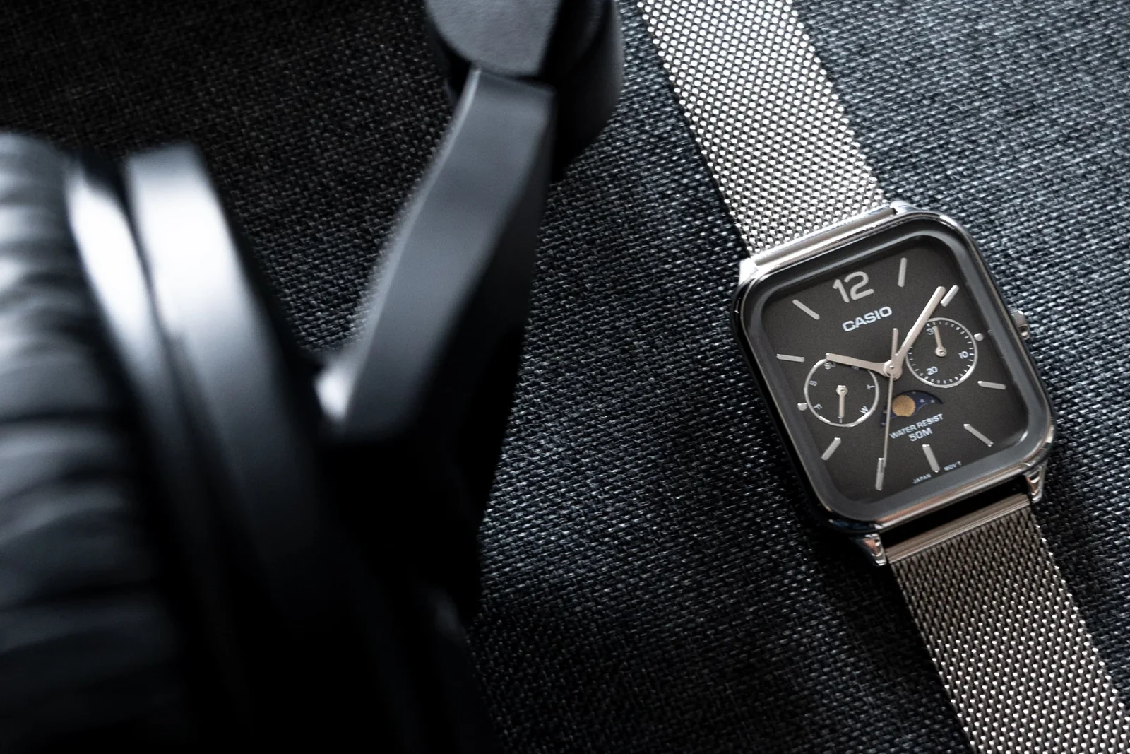 Ansicht der flach liegenden CASIO TIMELESS COLLECTION Armbanduhr MTP-M305M-8AV neben einem Kopfhörer.