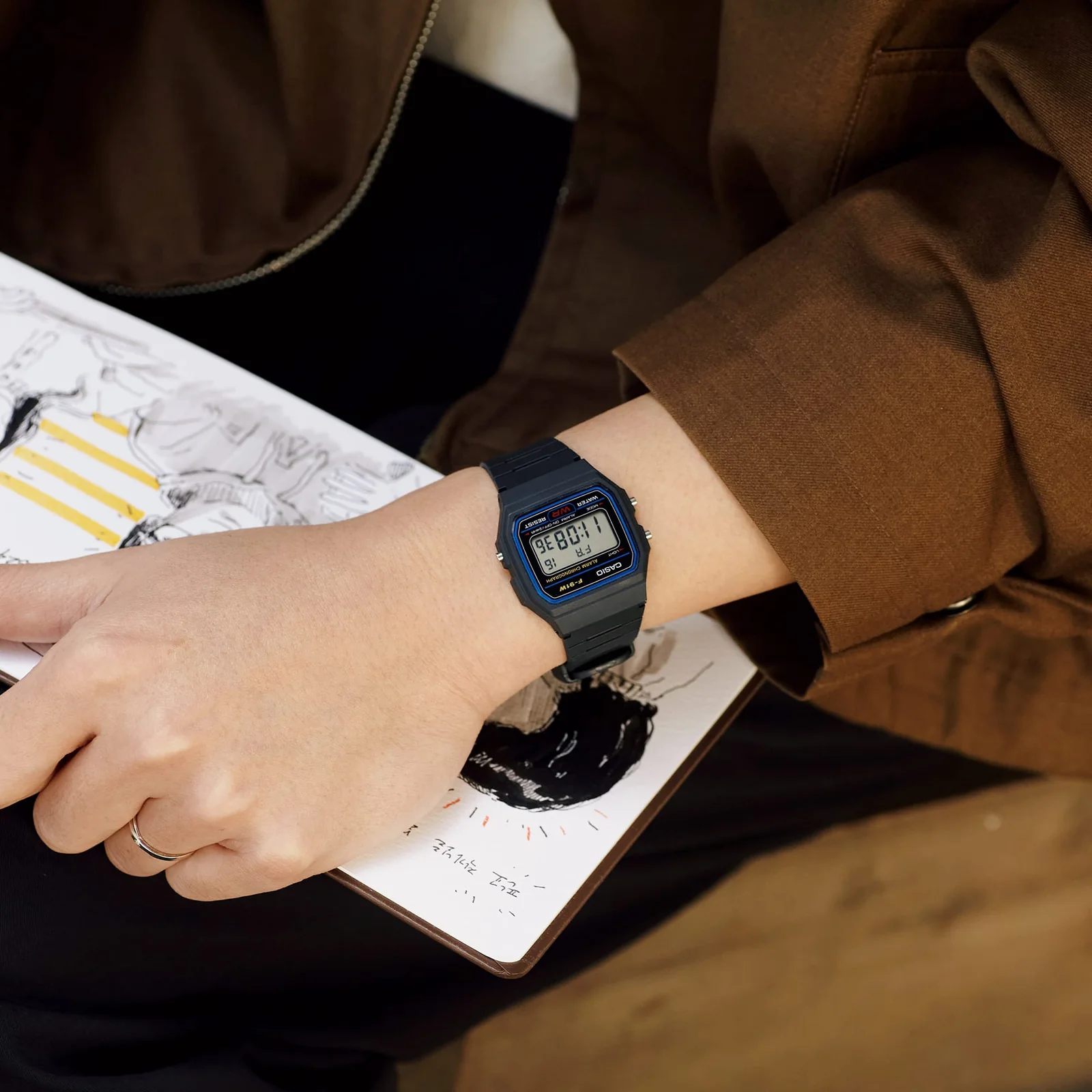 Eine Frau mit einer braunen Jacke trägt die Armbanduhr F-91W-1Y der CASIO TIMELESS COLLECTION am Handgelenk