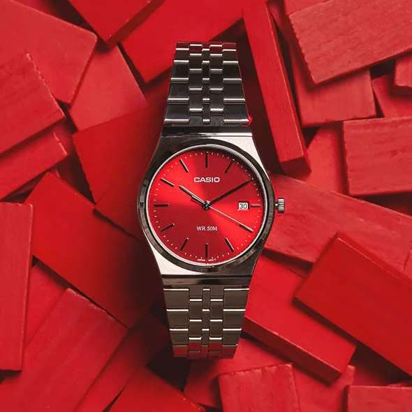 Die CASIO TIMELESS COLLECTION Armbanduhr MTP-B145D-4A2V dekorativ auf einer unsortierten Menge roter Täfelchen drapiert.