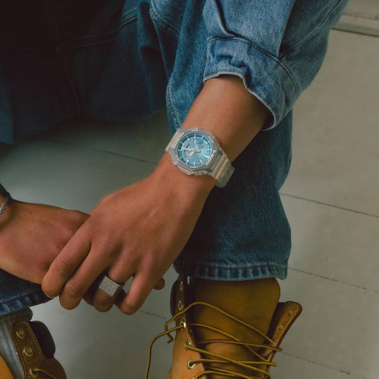 Die GA-2100BM-7A2 an dem Handgelenk eines Mannes, der eine Jeansjacke in Kombination mit einer Jeanshose trägt.