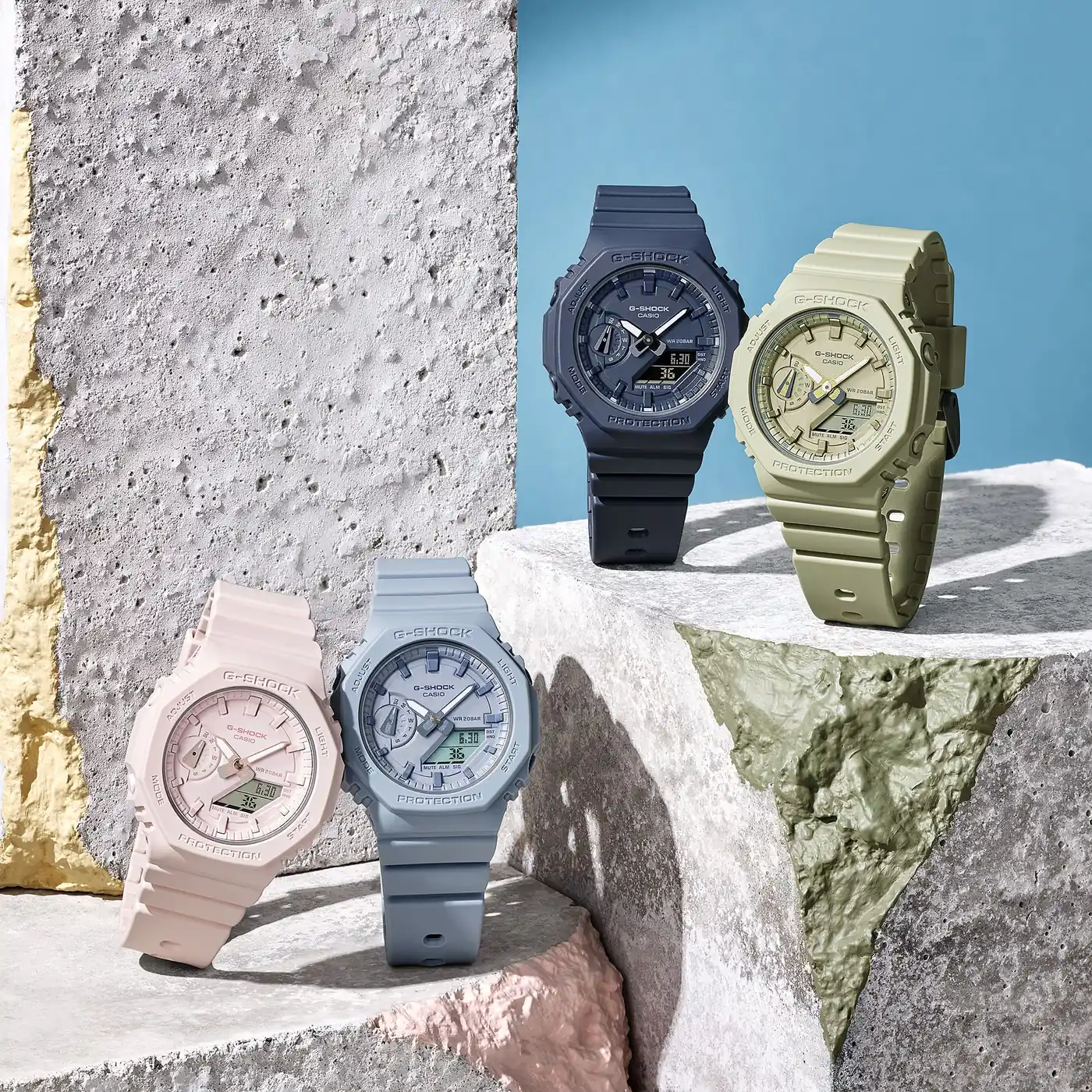 Die G-SHOCK WOMEN Armbanduhr GMA-S2100BA-2A1 neben den drei anderen Modellen der Serie in Hellrosa, Graublau und Hellgrün.