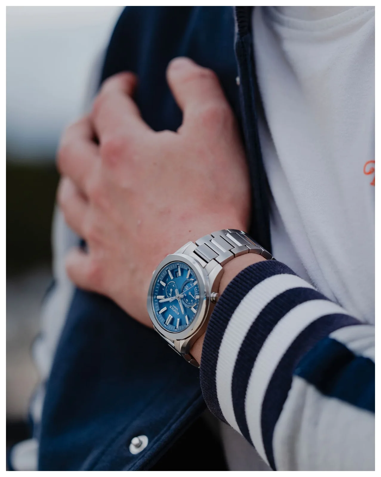 Ein Mann hat eine sportliche Sweatjacke an und trägt die analoge EDIFICE Armbanduhr EQB-1300D-2AEF am Handgelenk